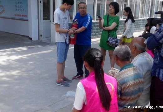 苗老师与志愿者为老人们演示讲解灭火器的使用方法